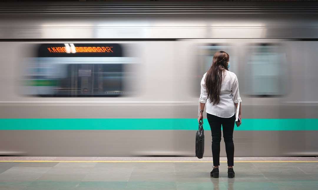 Kobieta w białej kurtce stoi obok pociągu puzzle online