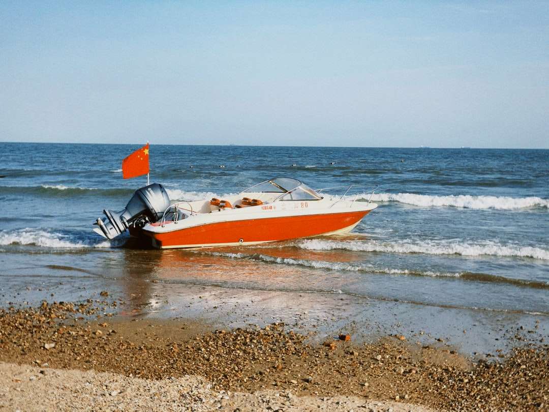 Biała i czerwona łódź na plaży w ciągu dnia puzzle online