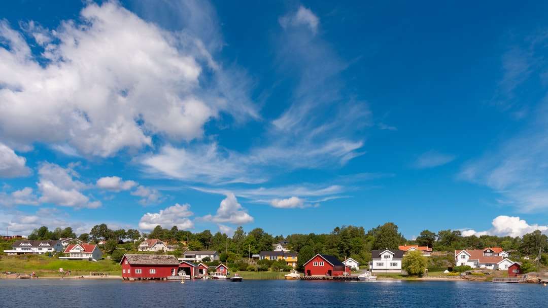 Czerwony i biały dom w pobliżu ciała wody pod błękitnym niebem puzzle online