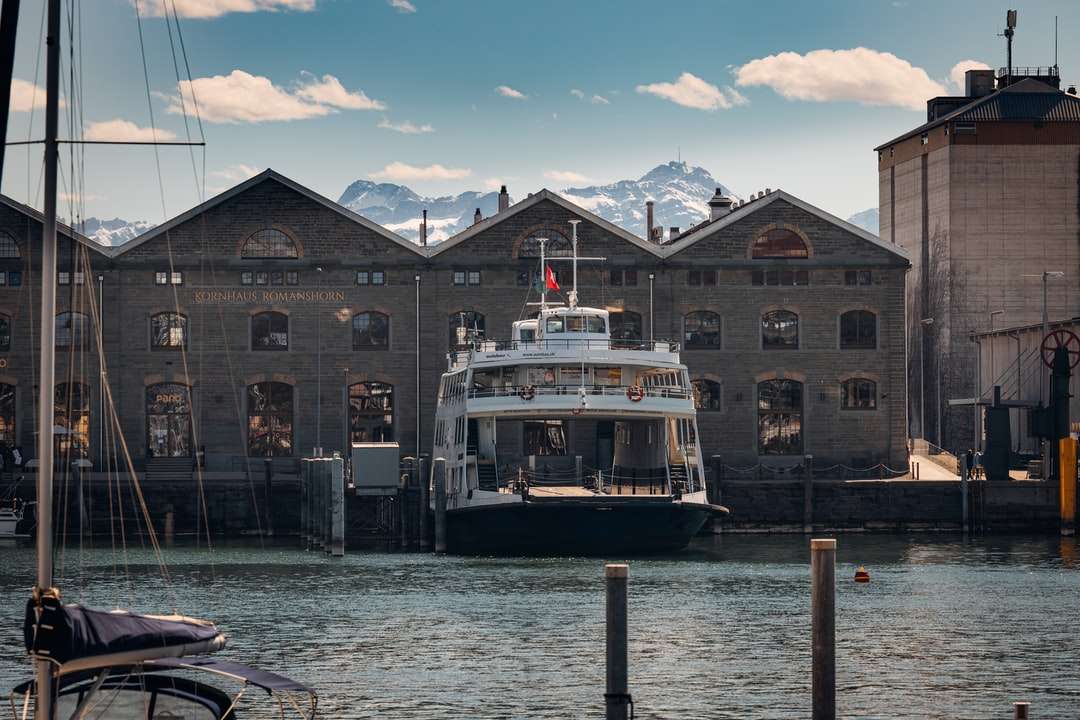 Biała i czarna łódź na wodzie blisko brązowego betonowego budynku puzzle online