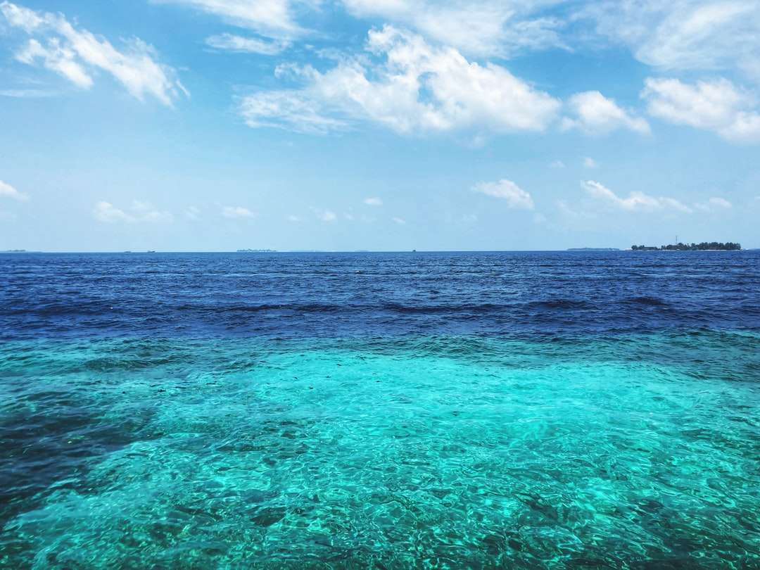 Błękitne morze pod błękitne niebo i białe chmury w ciągu dnia puzzle online