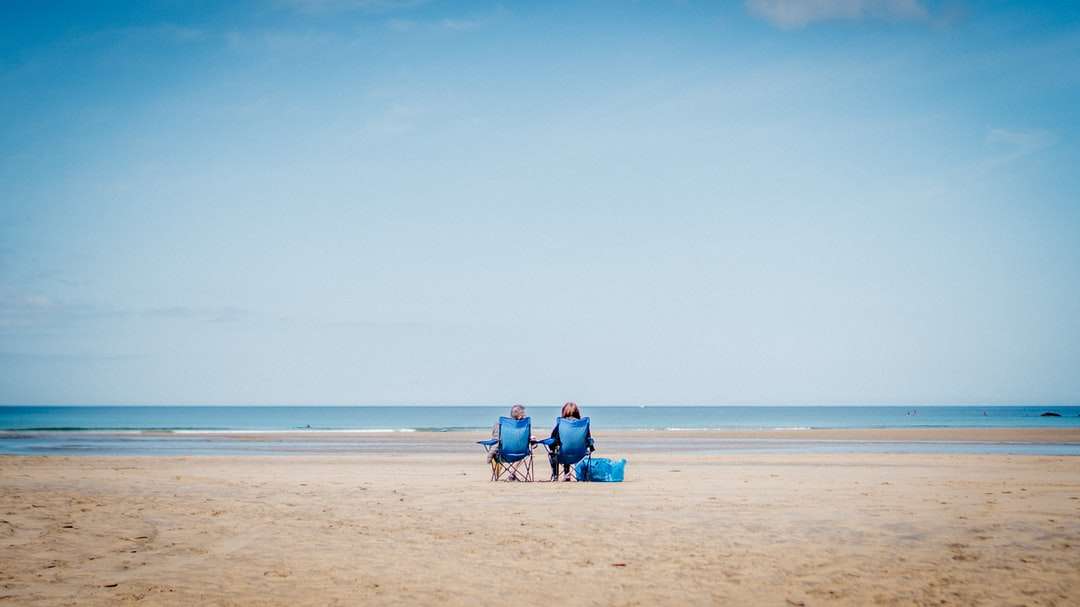 2 osoba siedzi na piasku plaży w ciągu dnia puzzle online