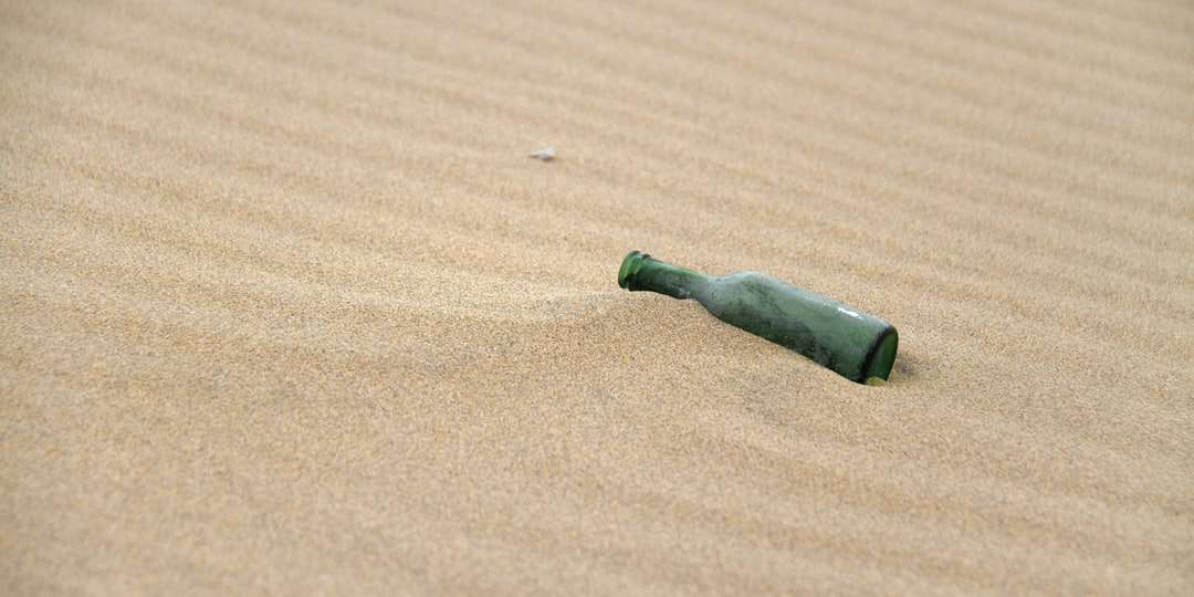 zielona i czarna szklana butelka na brązowym piasku puzzle online
