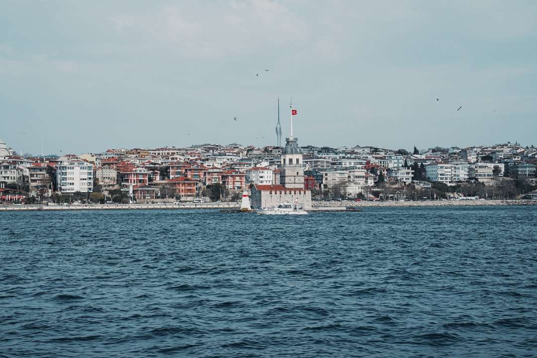 Biała łódź na morzu w pobliżu budynków miasta w ciągu dnia puzzle online