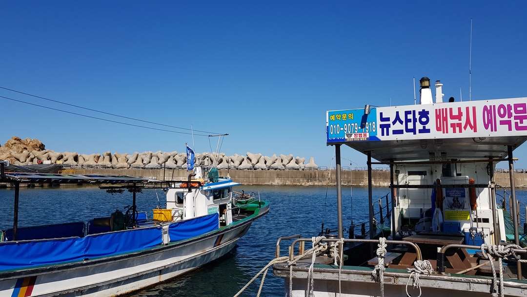 Niebieska i biała łódź na doku w ciągu dnia puzzle online