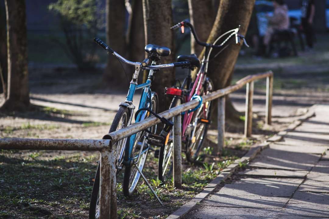 niebiesko-czarne rowery miejskie zaparkowane na brązowym drewnianym ogrodzeniu puzzle online