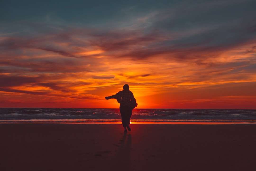 Sylwetka mężczyzna pozycja na plaży podczas zmierzchu puzzle online