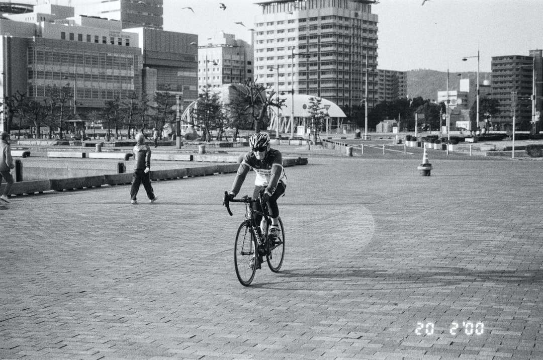 zdjęcie w skali szarości człowieka jadącego na rowerze na drodze puzzle online