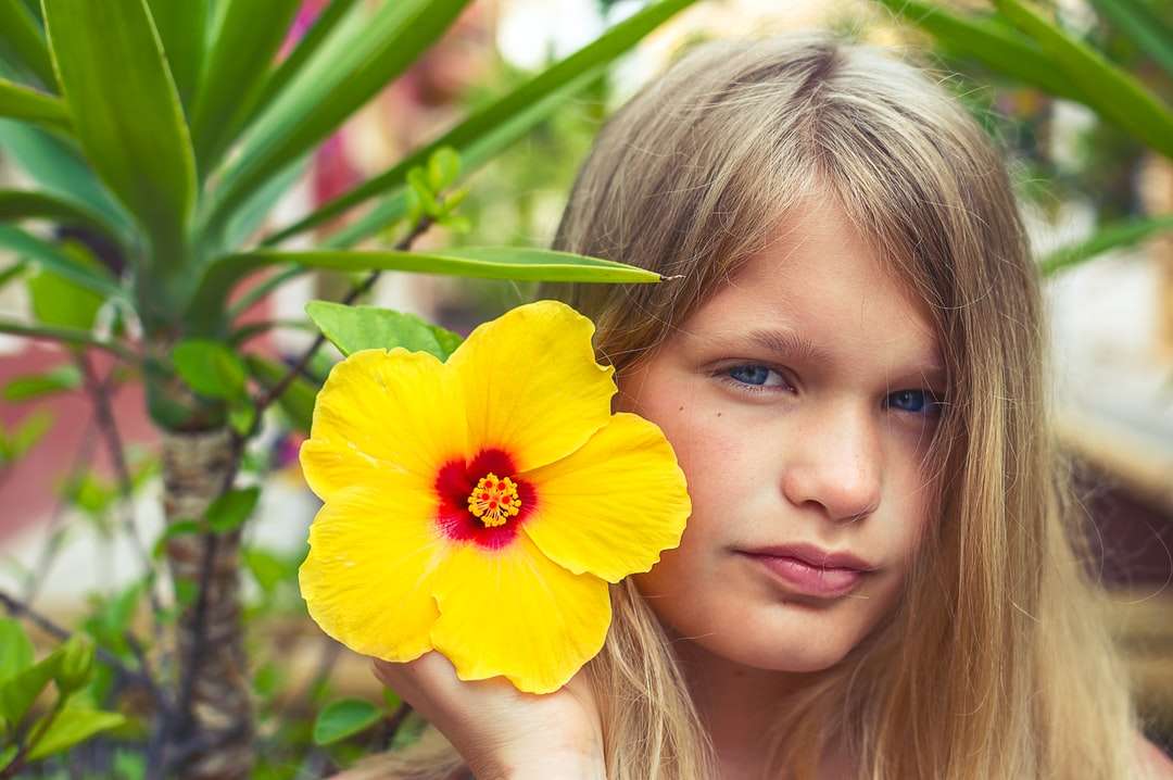Dziewczyna trzyma żółty kwiat podczas dnia puzzle online