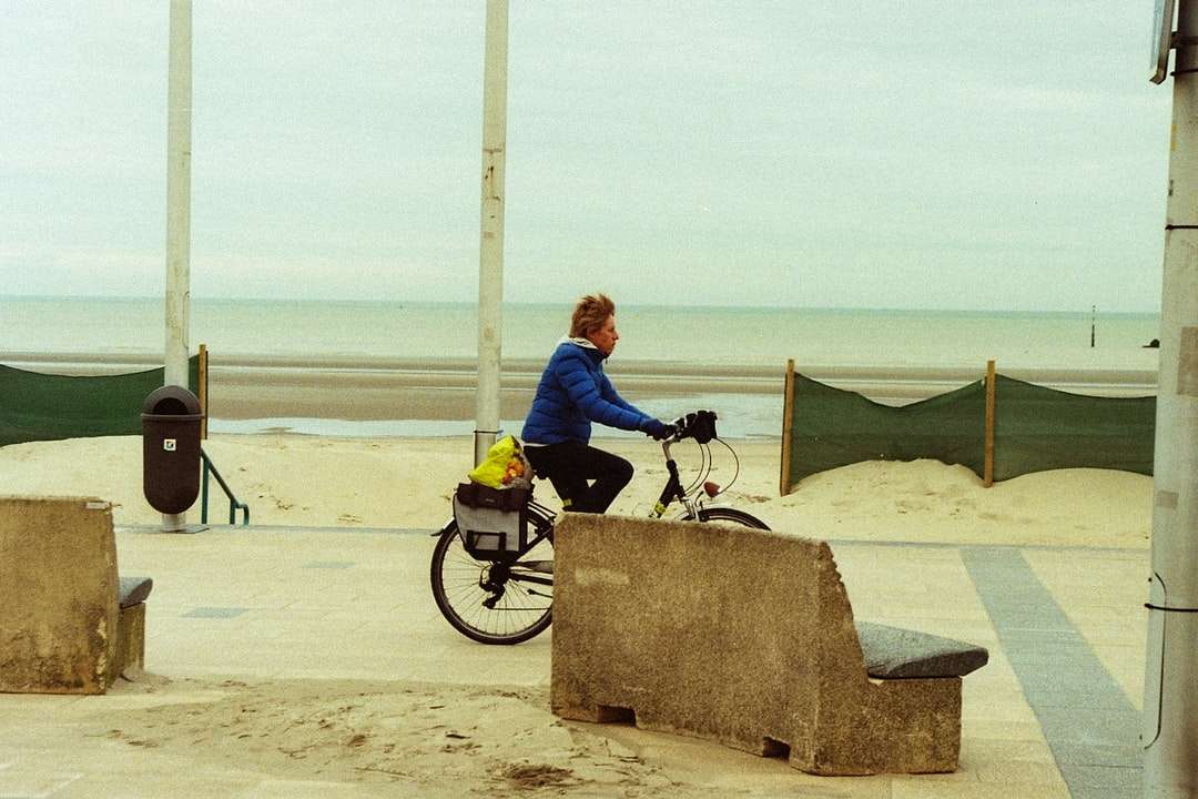 Mężczyzna w niebieskiej kurtce jazda na czarnym motocyklu na plaży puzzle online