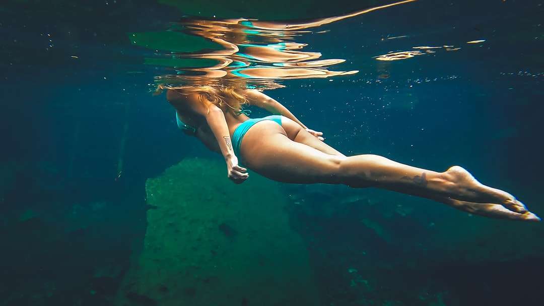 Kobieta w niebieskim bikini pływanie w wodzie puzzle online