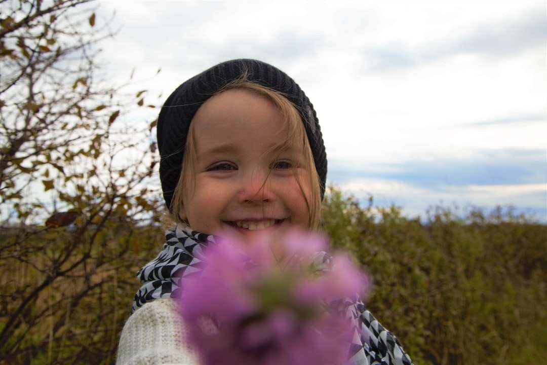 Dziewczyna w białym dzianina sweter gospodarstwa różowy kwiat puzzle online