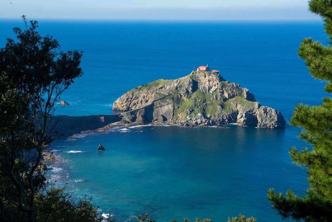 Zielona i brązowa góra obok błękitnego morza w ciągu dnia puzzle online