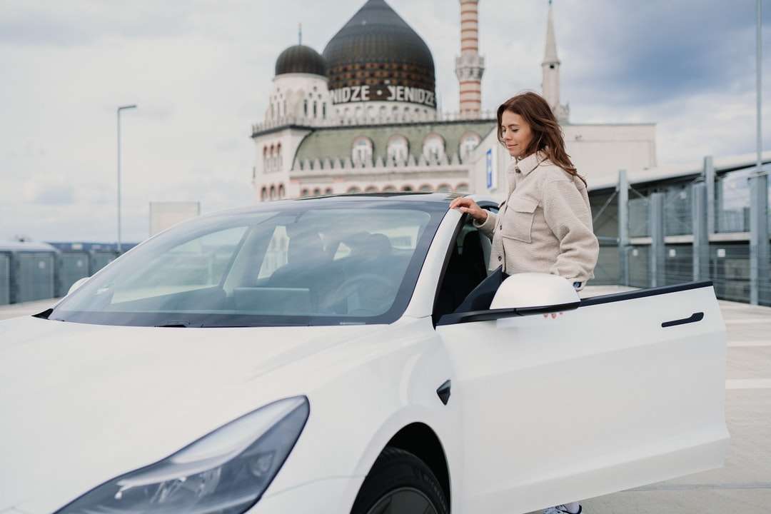 Kobieta w szarym blezer stoi obok białego samochodu puzzle online