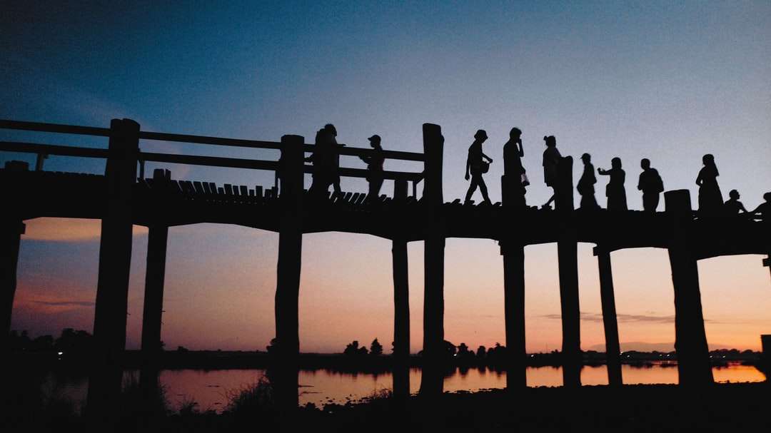Sylwetka osób stojących na drewnianym doku podczas zachodu słońca puzzle online