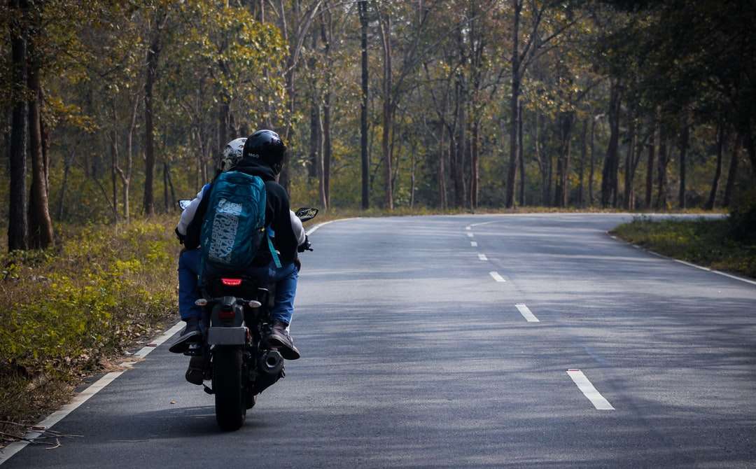 Mężczyzna w czarnej kurtce jedzie motocyklu na drodze w ciągu dnia puzzle online