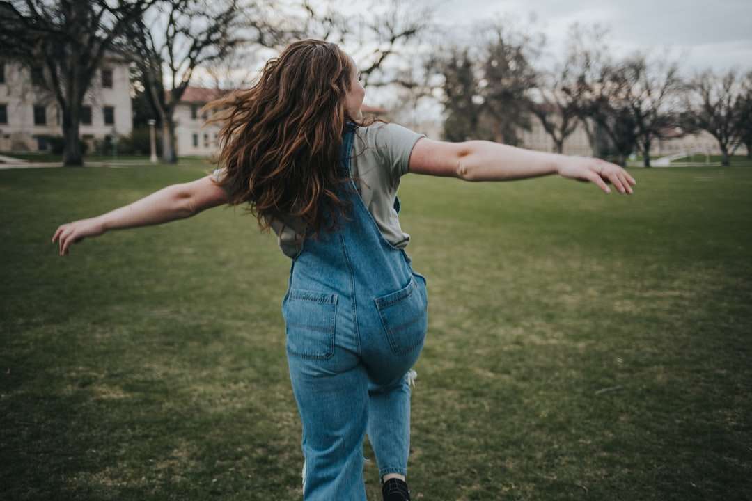 Kobieta w błękitnych dżinsowych dżinsach stoi na zielonej trawy polu puzzle online