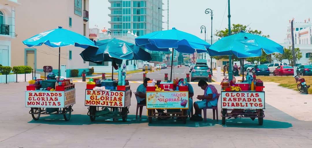 ludzie siedzący na czerwonych krzesłach pod niebieskim parasolem puzzle online