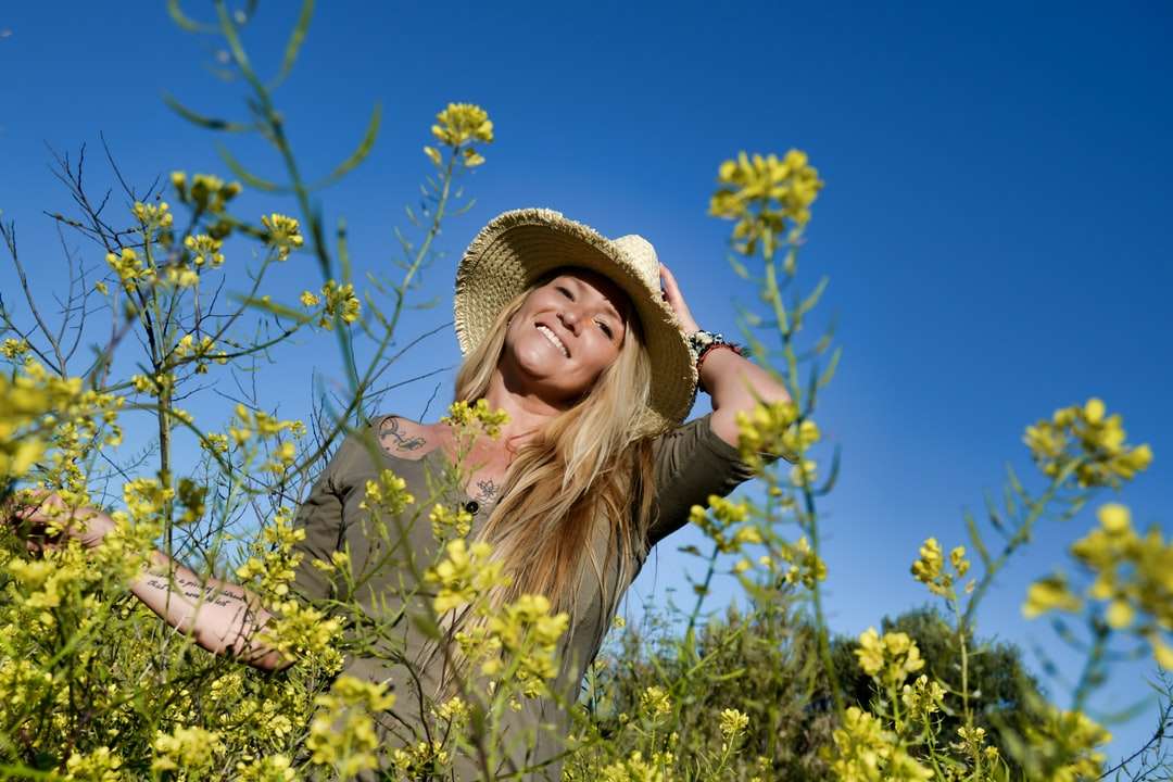 Dziewczyna w brown słońce kapeluszu stoi na żółtym kwiatu polu puzzle online