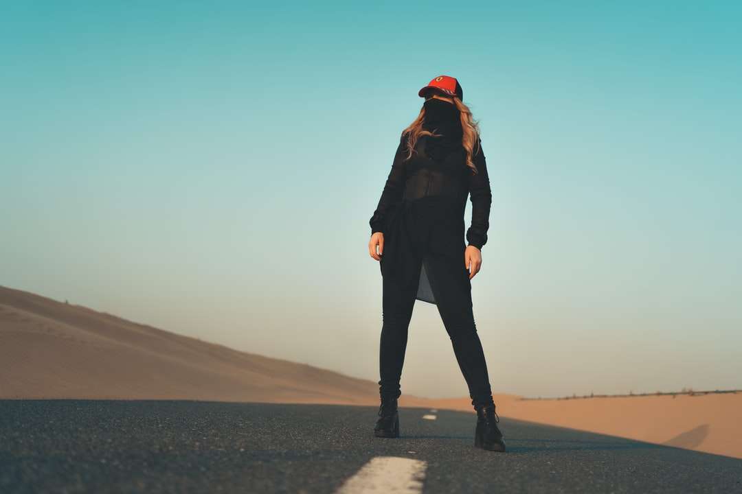 Kobieta w czarnej kurtce i spodniach stojących na szarym piasku puzzle online