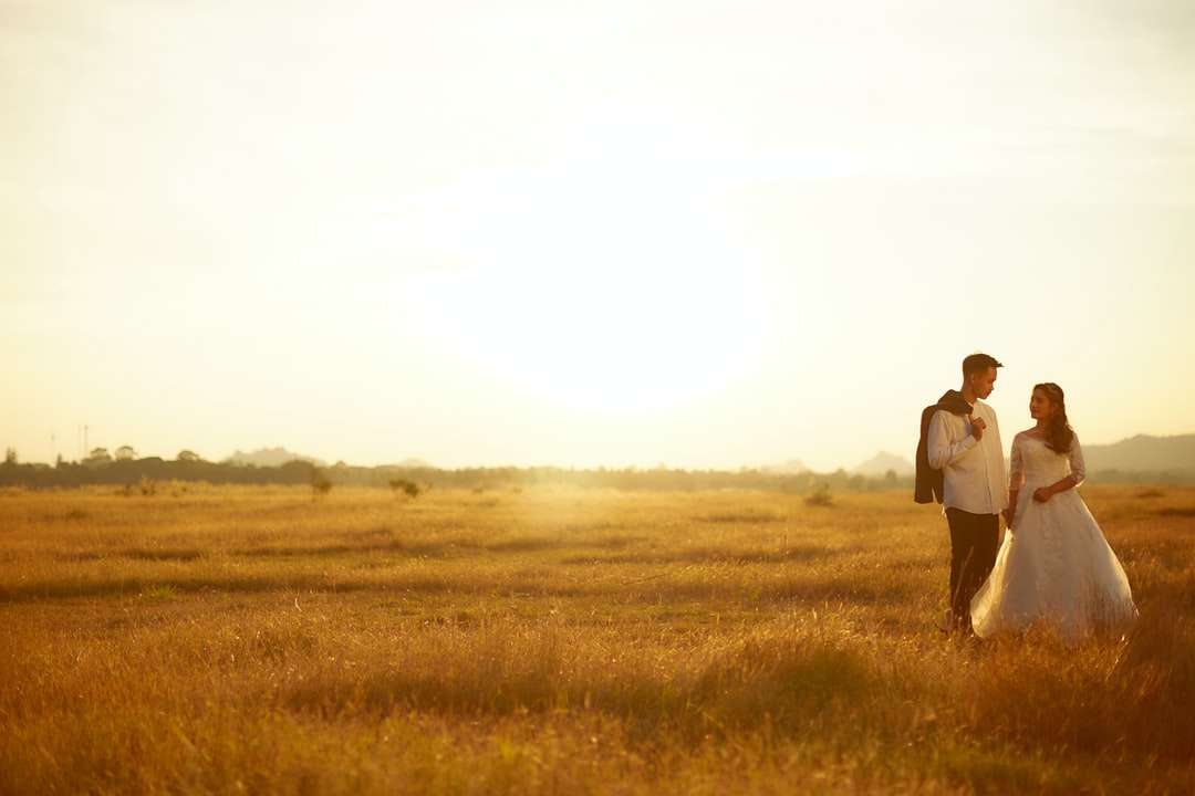 mężczyzna i kobieta chodzą po brązowym polu trawy w ciągu dnia puzzle online