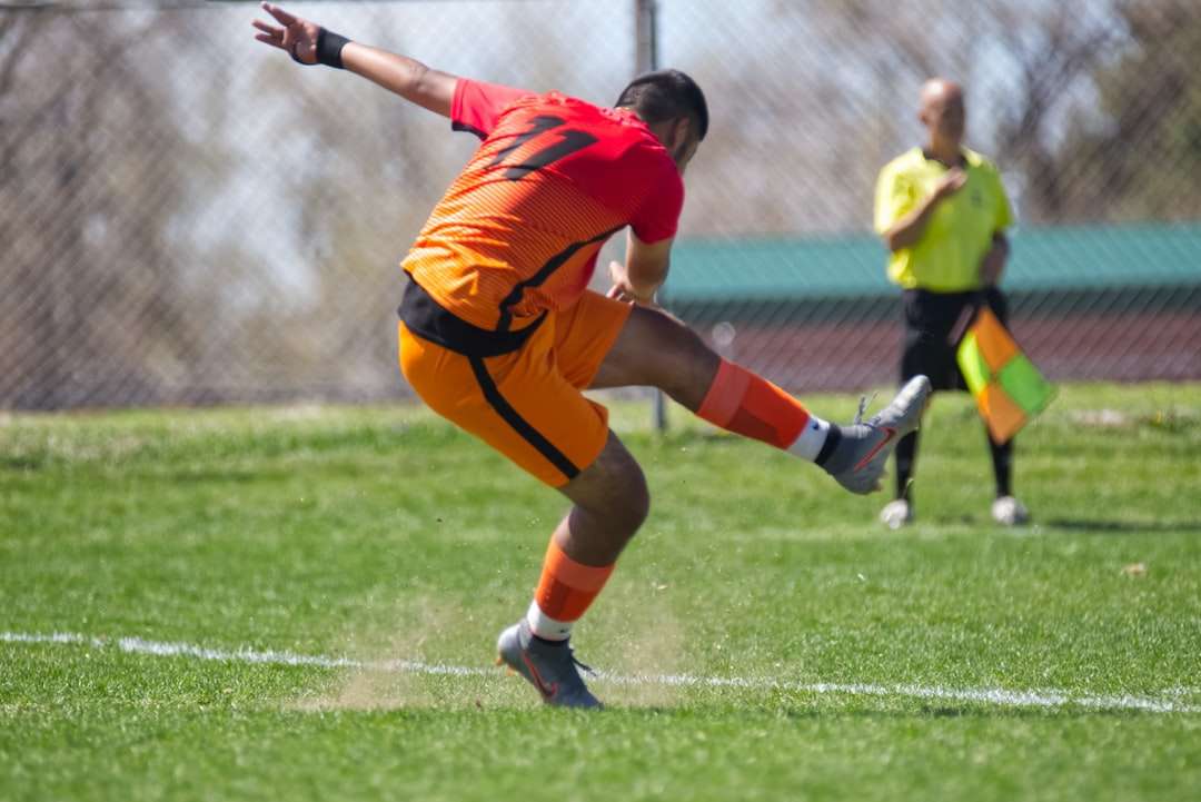 Mężczyzna w koszulce pomarańczowej koszulki kopania piłki nożnej puzzle online