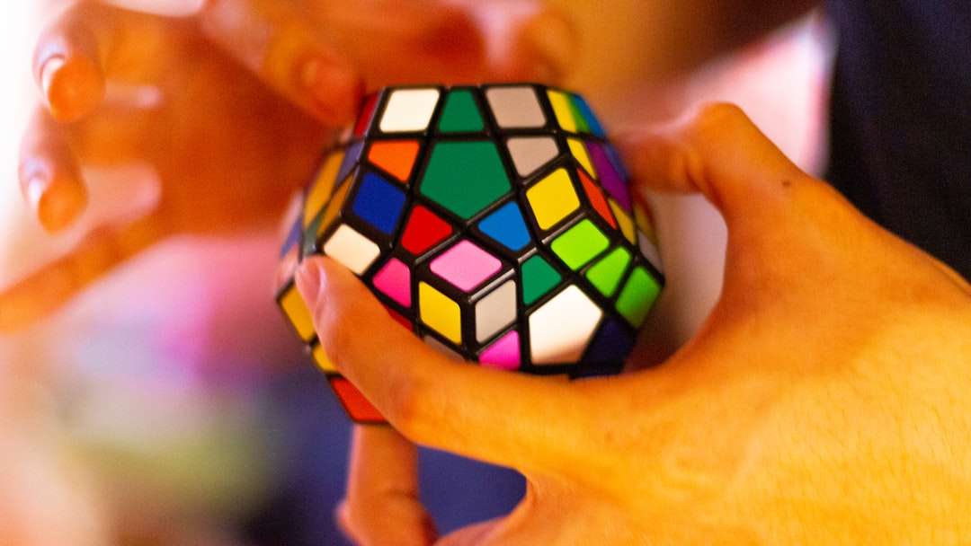 osoba trzyma 3 x 3 Rubiks Cube puzzle online