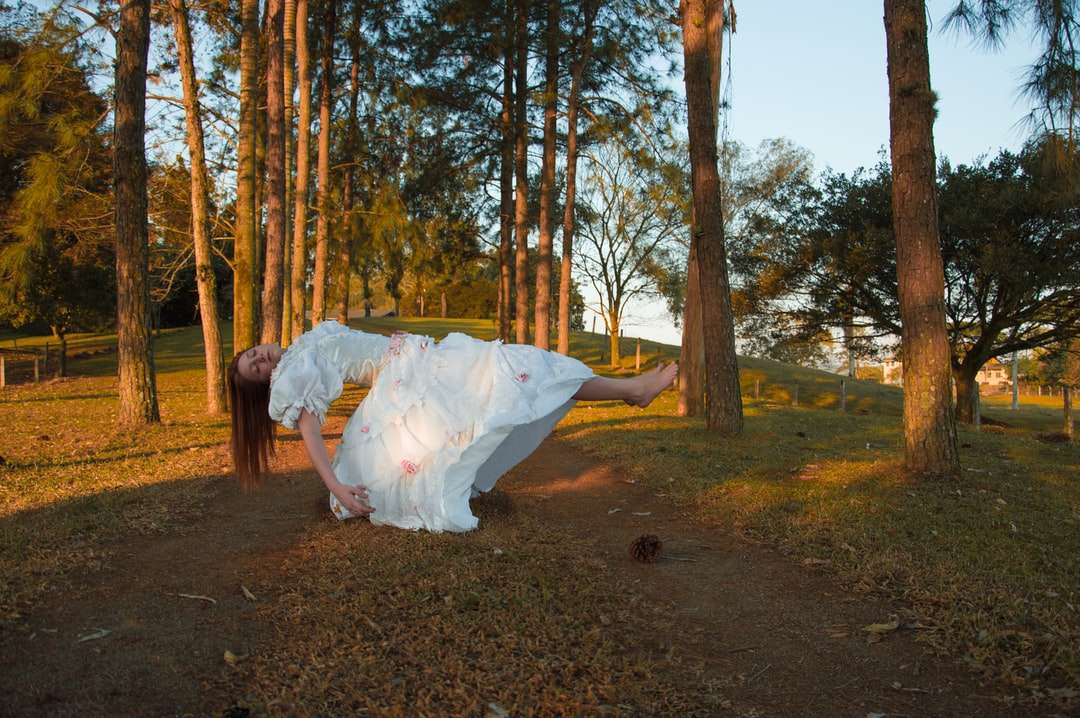 Kobieta w białej sukni spaceru na brązowej drodze gruntowej puzzle online