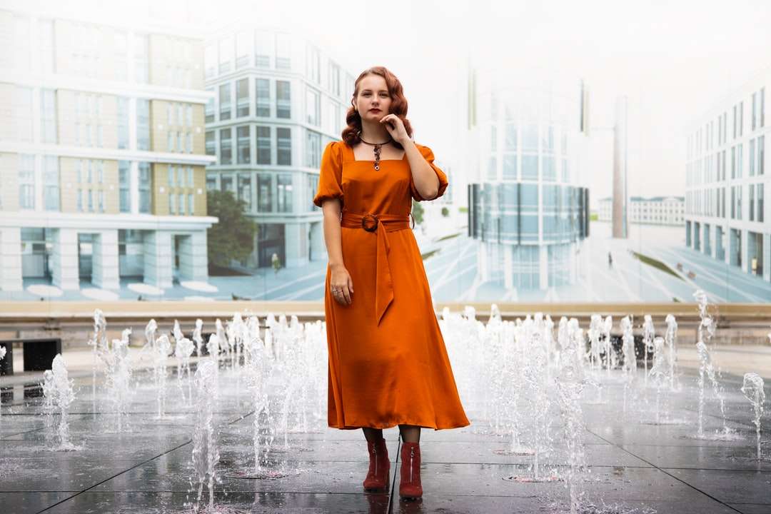 kobieta w pomarańczowej sukience stojąca na fontannie puzzle online