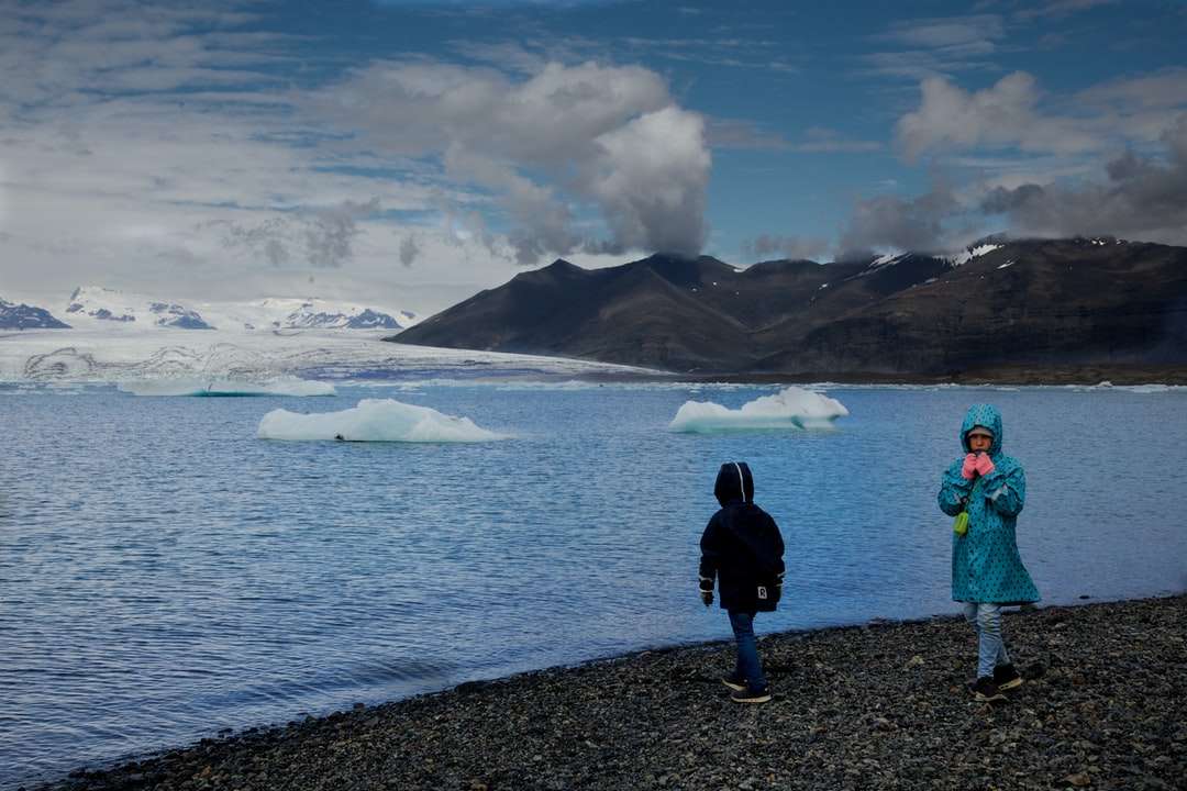 2 osoba stojąca na szarej skale w pobliżu wody puzzle online