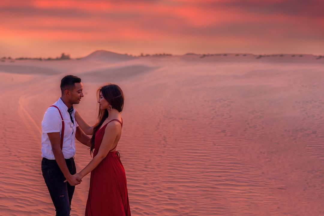 Mężczyzna i kobieta stoi na brzegu morza podczas zachodu słońca puzzle online