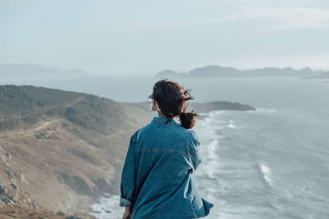 kobieta w niebieskiej dżinsowej kurtce stojąca na klifie w ciągu dnia puzzle online