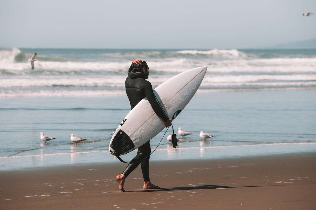 Kobieta w czarnym kombinezonie mienia białej surfboard puzzle online