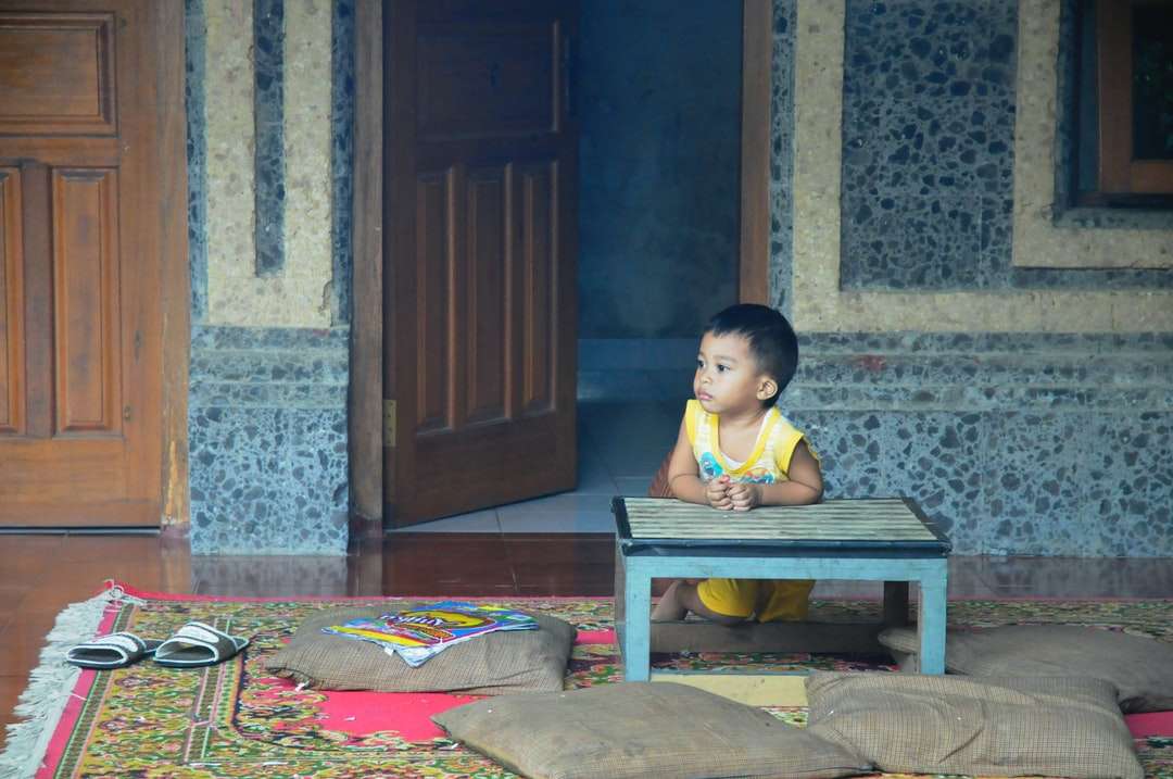 chłopiec w żółtym podkoszulku siedzący na brązowej drewnianej ławce puzzle online
