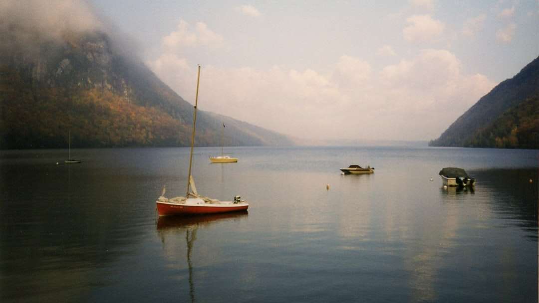 Biała i brązowa łódź na wodzie w pobliżu góry w ciągu dnia puzzle online