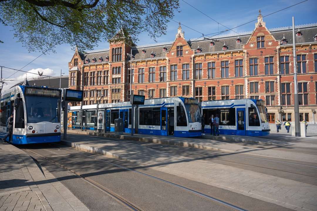 Niebieski i żółty tramwaj na drodze w pobliżu brązowego budynku puzzle online