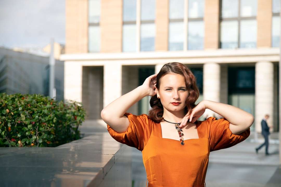 Kobieta w pomarańczowym długim rękawie koszula stoi na chodniku puzzle online