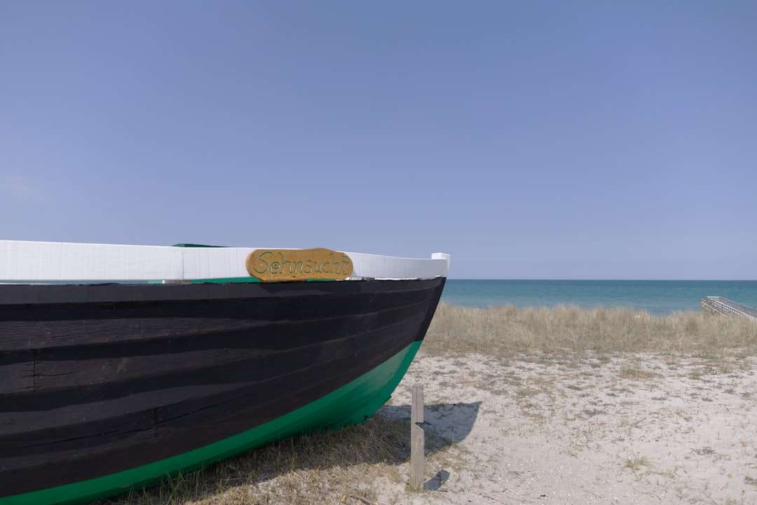 Niebieska i biała łódź na brzegu plaży w ciągu dnia puzzle online