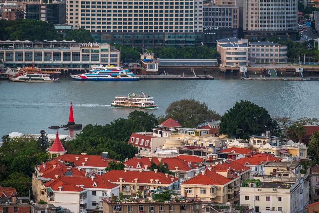 Biała i niebieska łódź na wodzie w pobliżu budynków miasta puzzle online