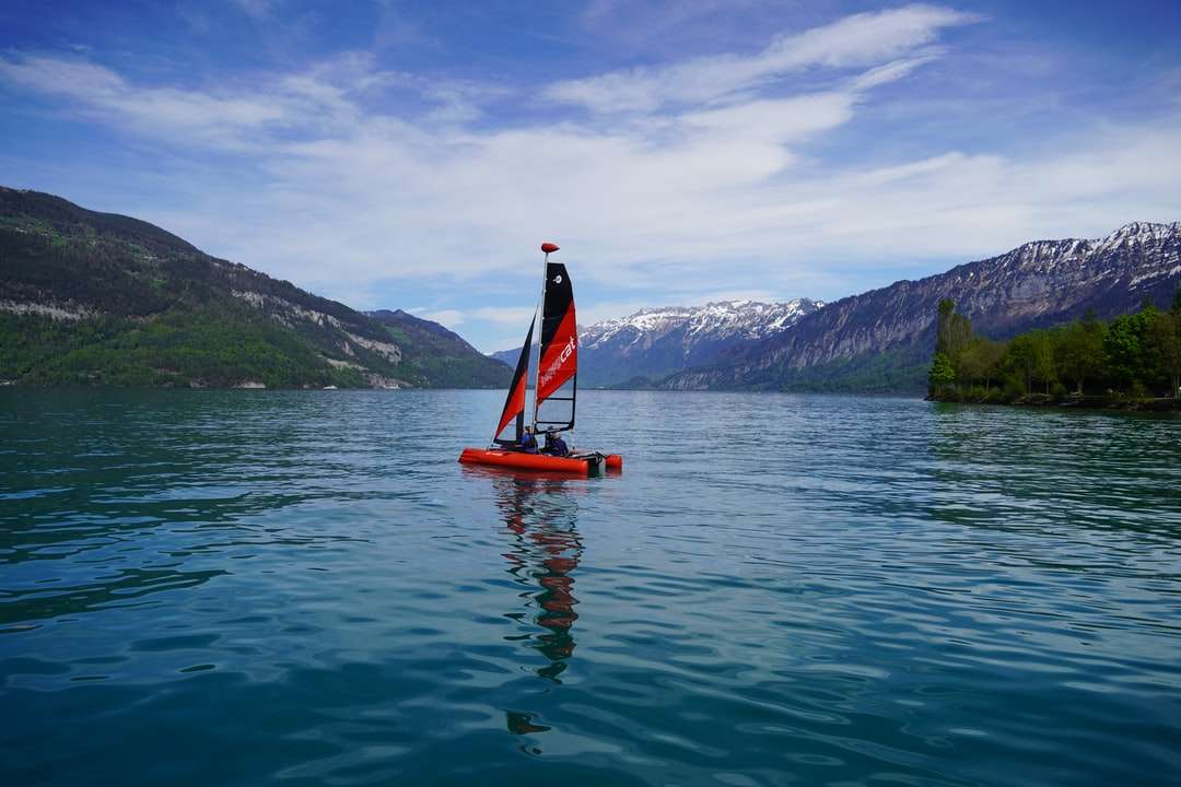 osoba w czerwonej i czarnej łodzi żaglowej na ciele wody puzzle online