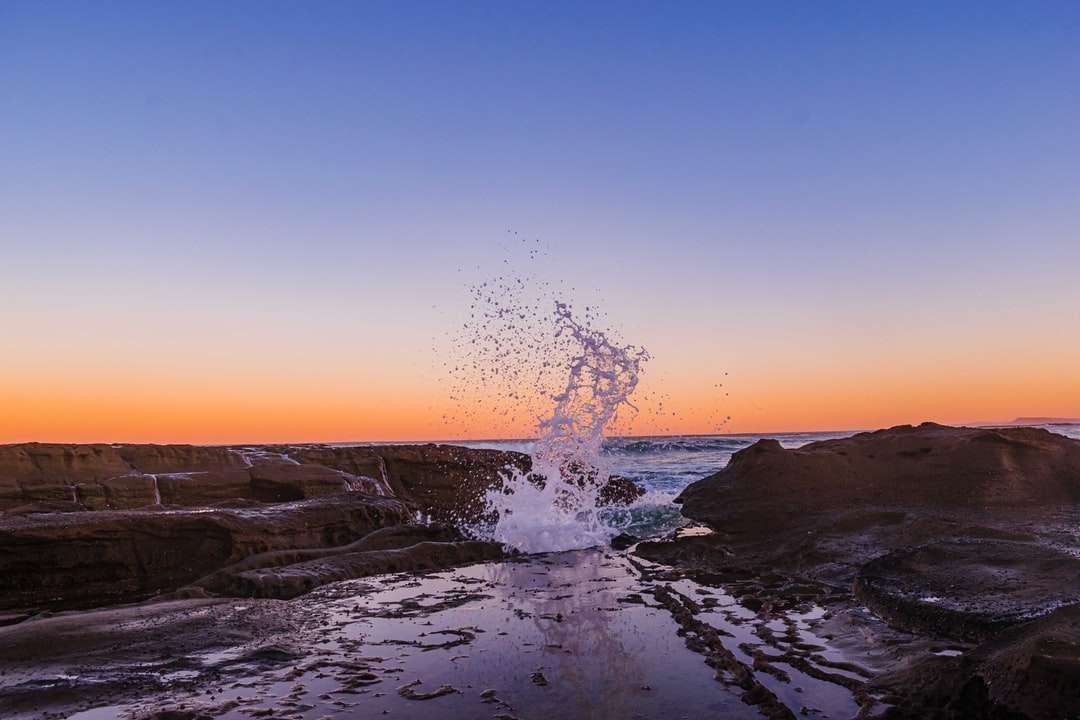 Plusk wody na skalistym brzegu podczas zachodu słońca puzzle online