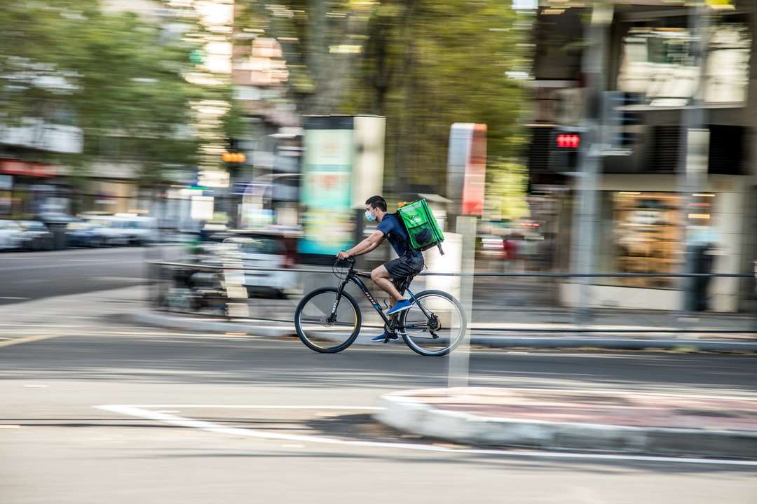 mężczyzna w zielonej koszuli jedzie rowerem po drodze w ciągu dnia puzzle online