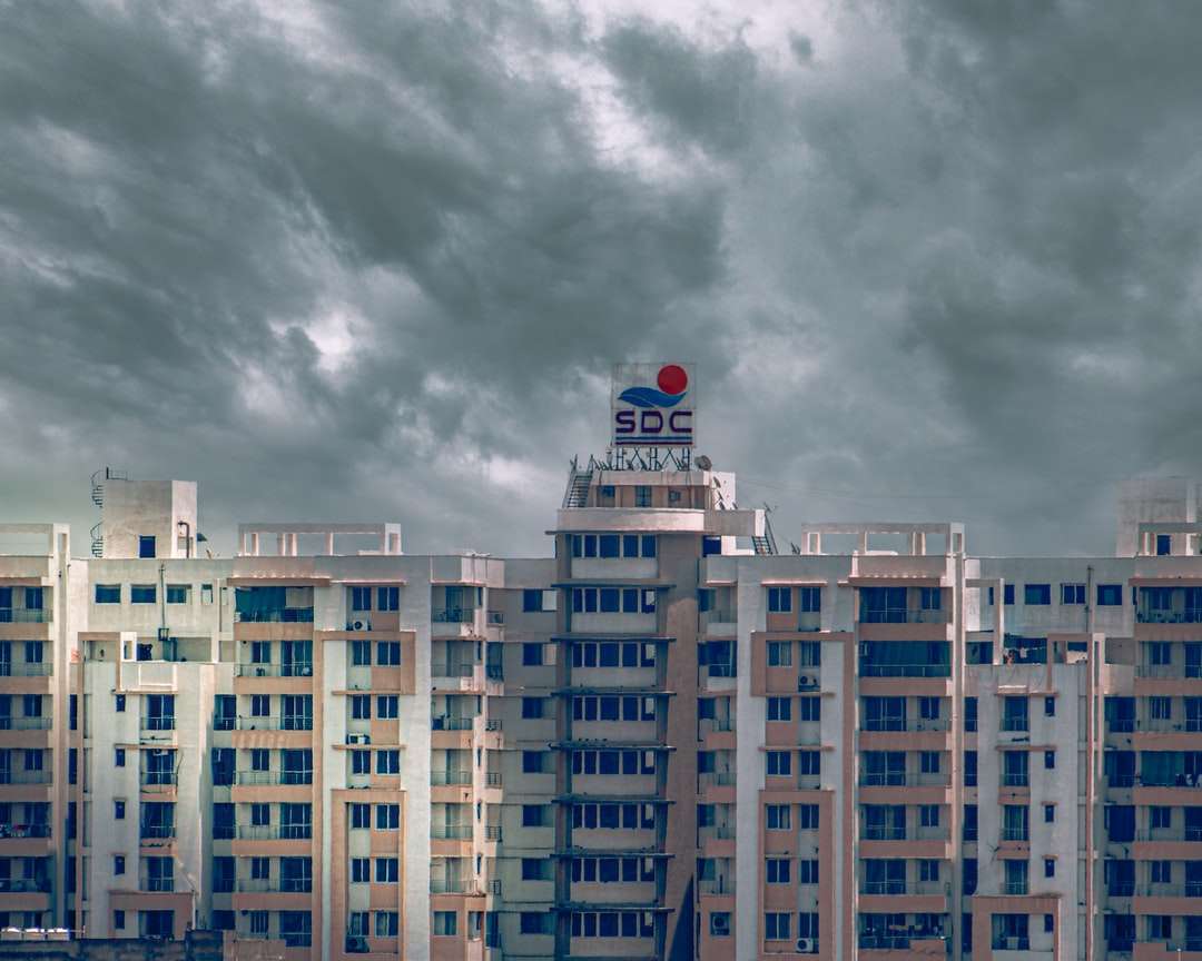 Biały i niebieski betonowy budynek pod szarymi chmurami puzzle online