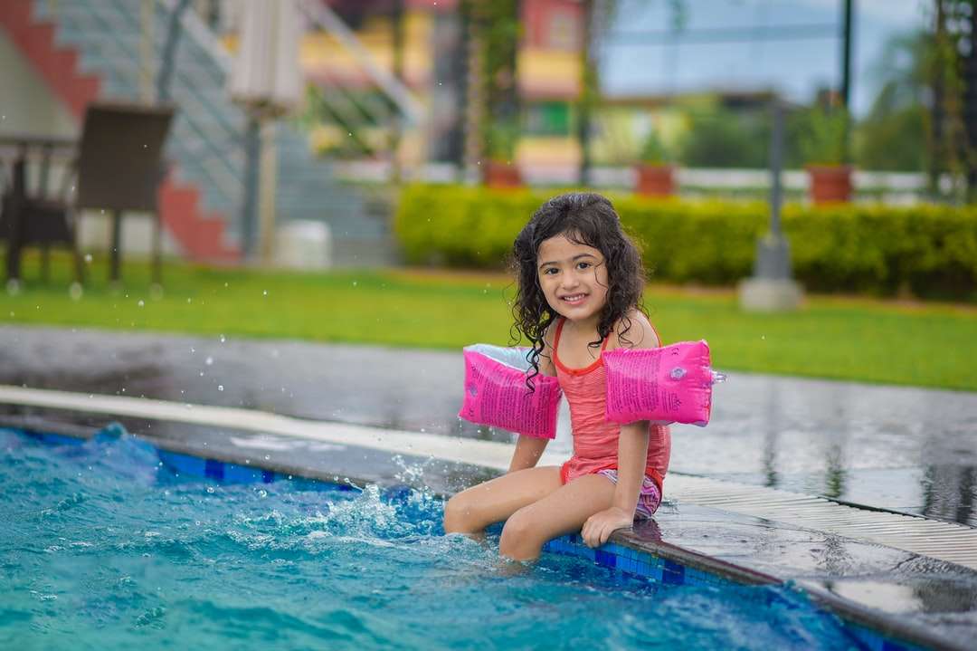 Dziewczyna w różowej koszuli siedzi na niebieskim basenie puzzle online