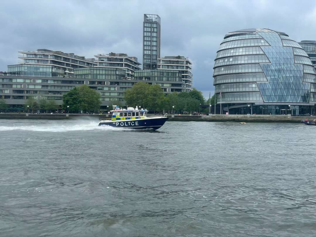 Biała i niebieska łódź na wodzie w pobliżu budynków miasta puzzle online