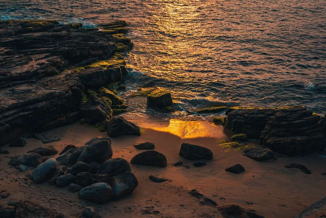 Brązowe skały na brzegu morza podczas zachodu słońca puzzle online