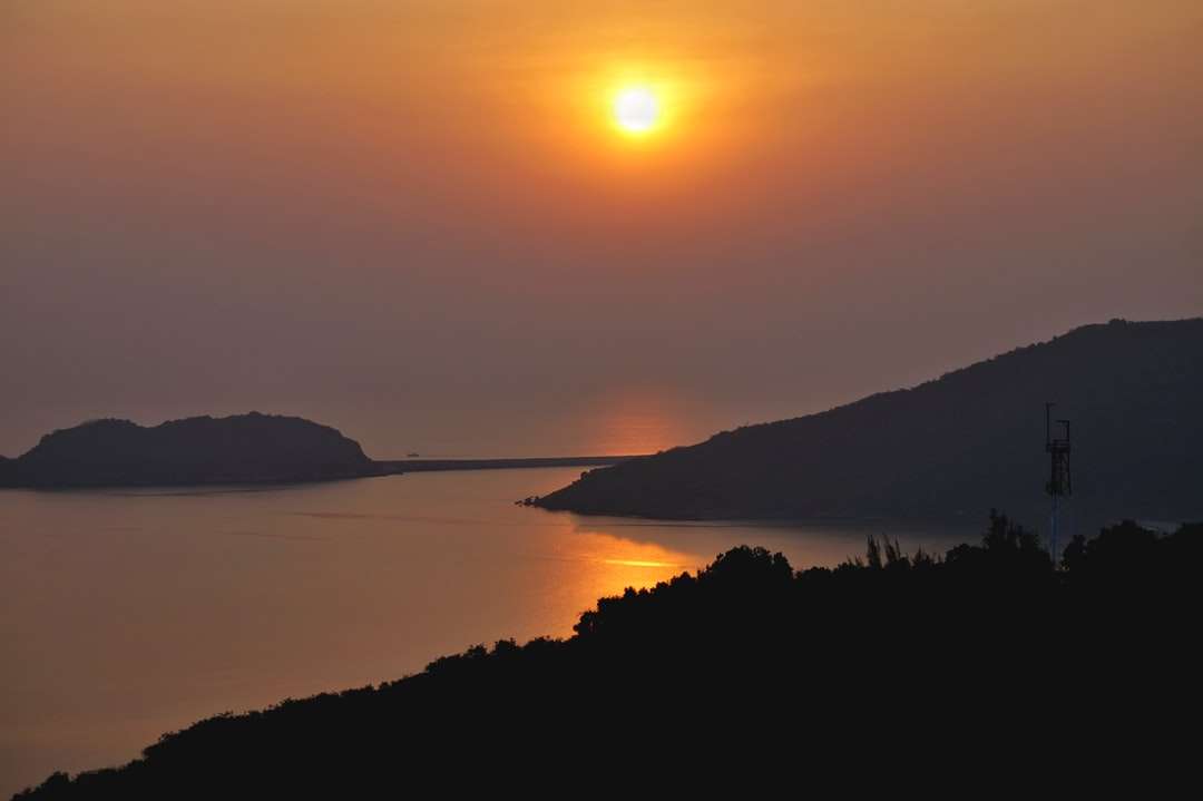 Sylwetka góry w pobliżu wody podczas zachodu słońca puzzle online