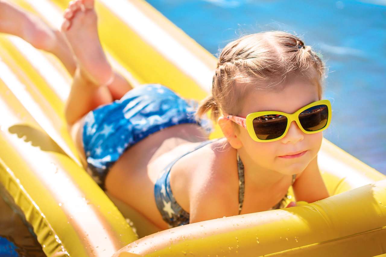 Mała dziewczynka w okularach przeciwsłonecznych pływa na materac puzzle online