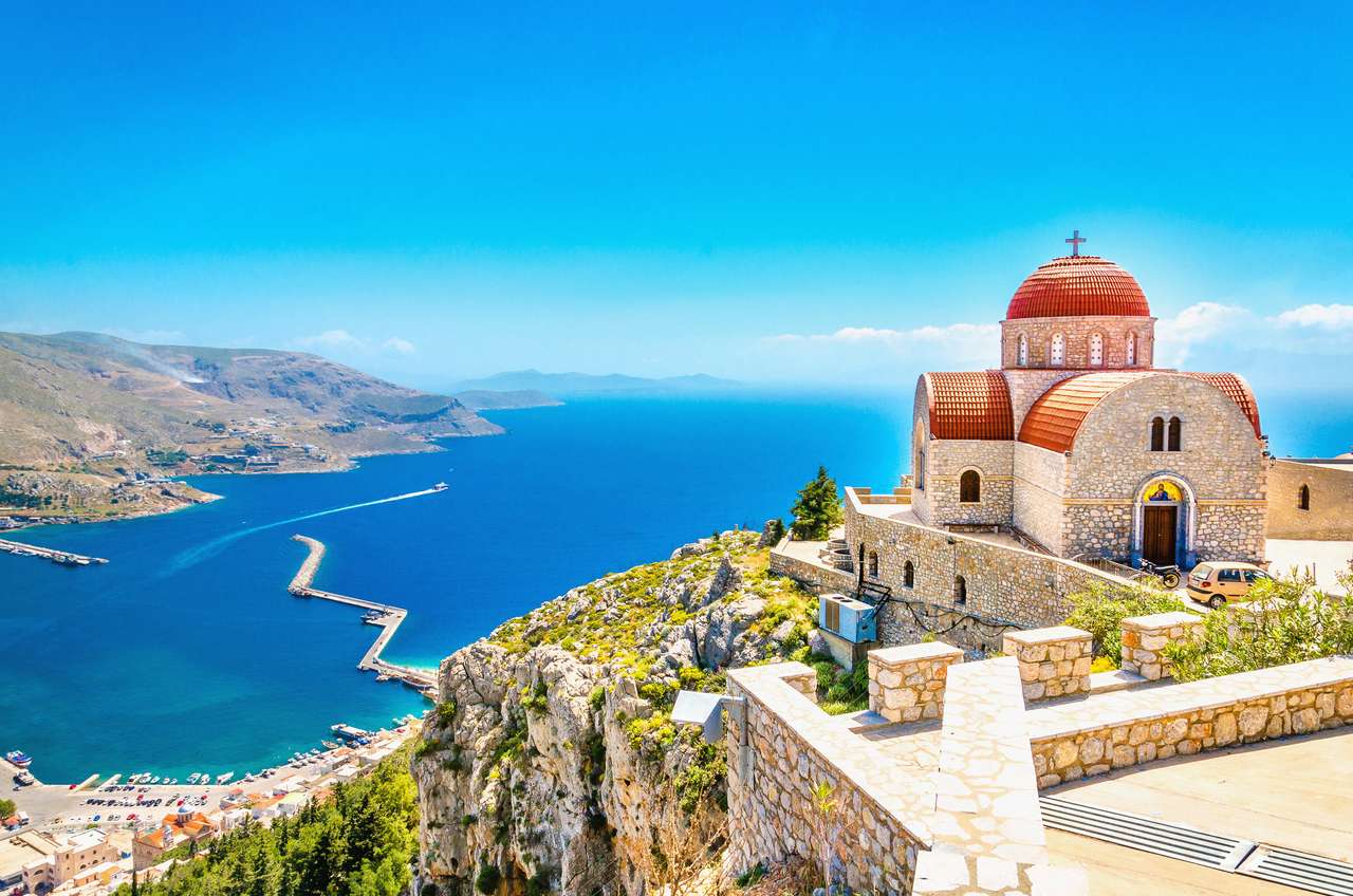Niesamowity widok na zdalny kościół z czerwonym dachem na klifie morza, Grecja puzzle online