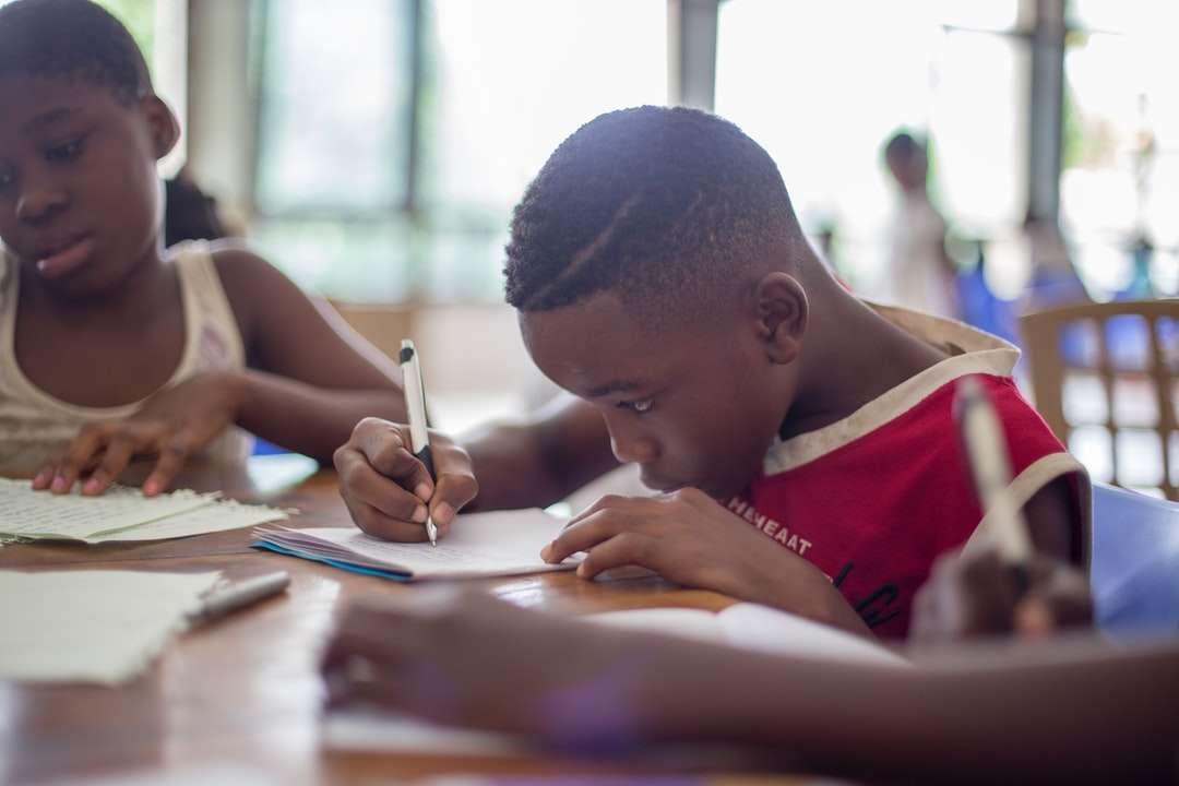 chłopiec piszący na papierze do drukarki w pobliżu dziewczyny puzzle online